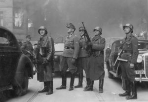 Jürgen Stroop (center, in a field cap) with his men observe the burning of Warsaw Ghetto during the suppression of the Warsaw Ghetto uprising, 1943. (Image: Wikipedia Commons)